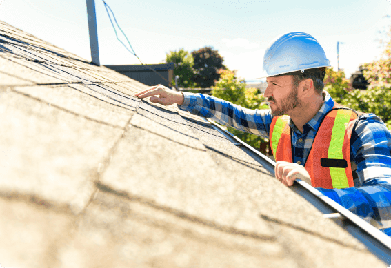 a person wearing a hard hat and safety vest pointing at a wall