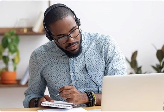 a person wearing glasses and a headset using a laptop