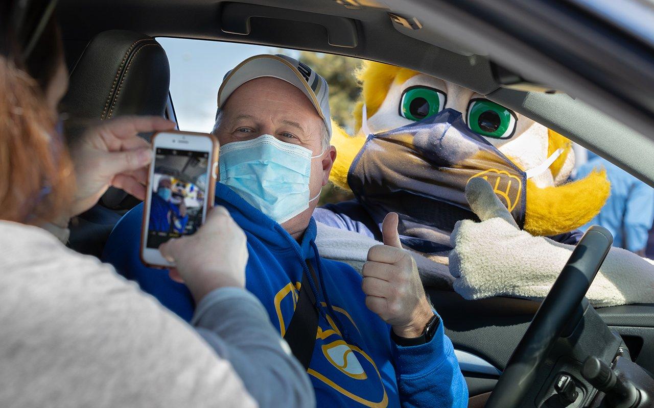 a person in a garment holding a phone in a car