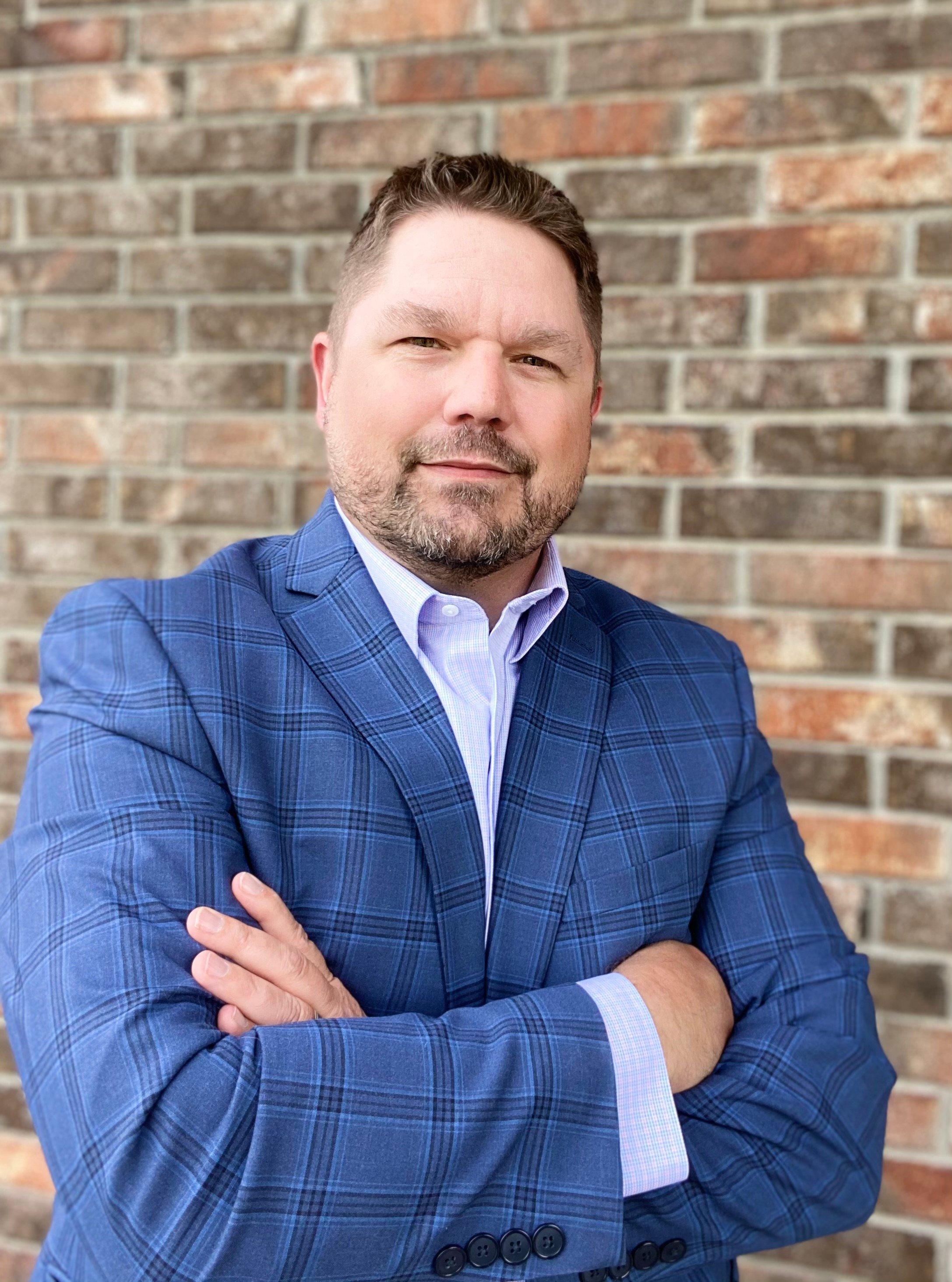 a man in a suit leaning against a brick wall