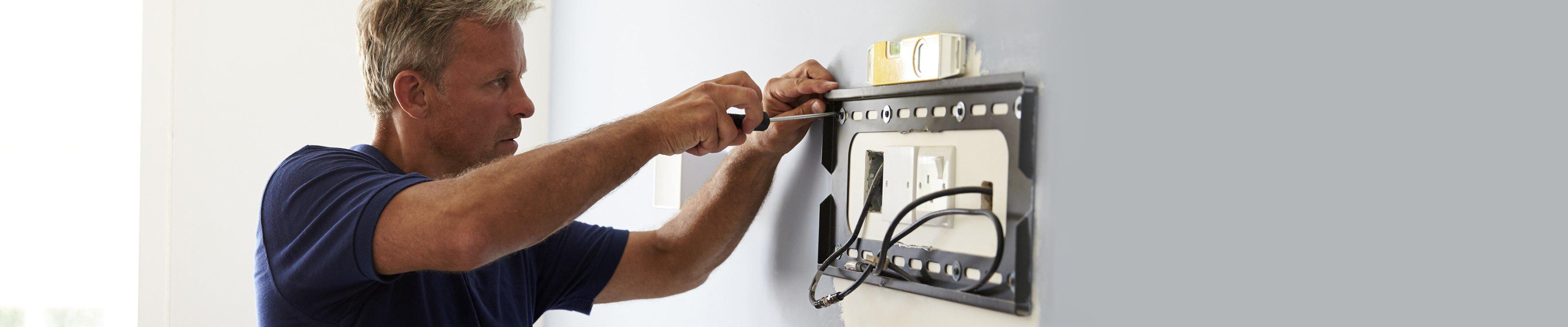 Man mounting TV on wall.