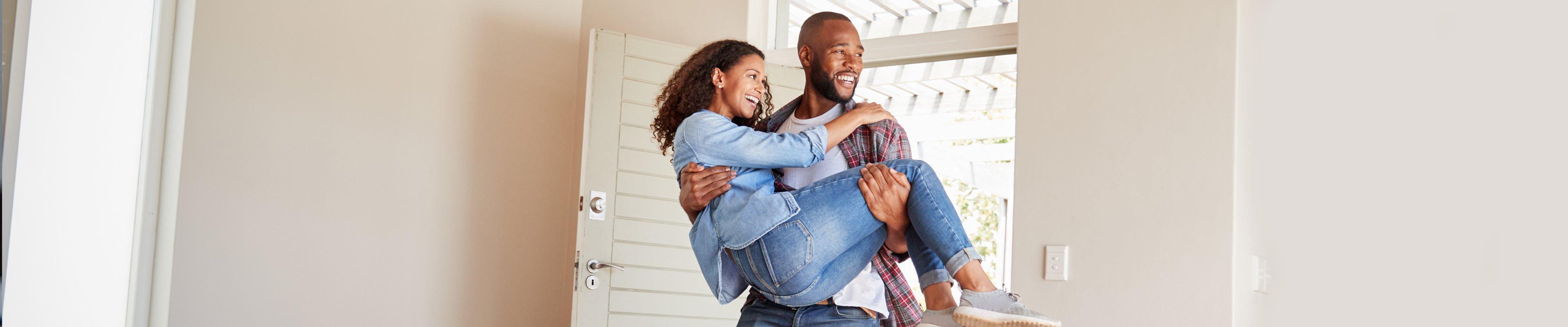 Young couple walking through the threshold of their new home.