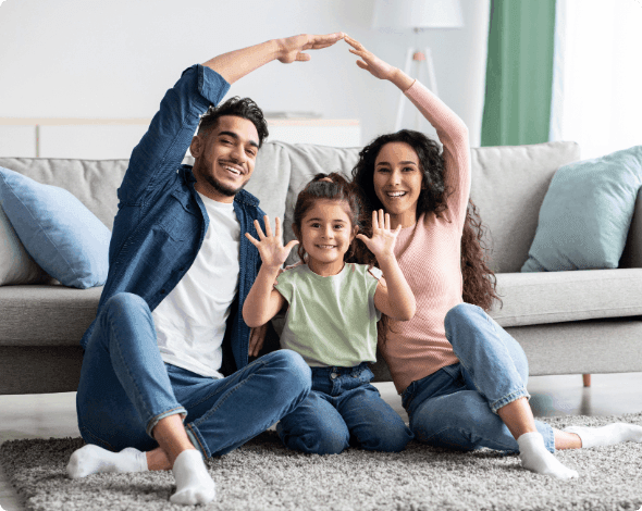 Happy family sitting in front of their couch.