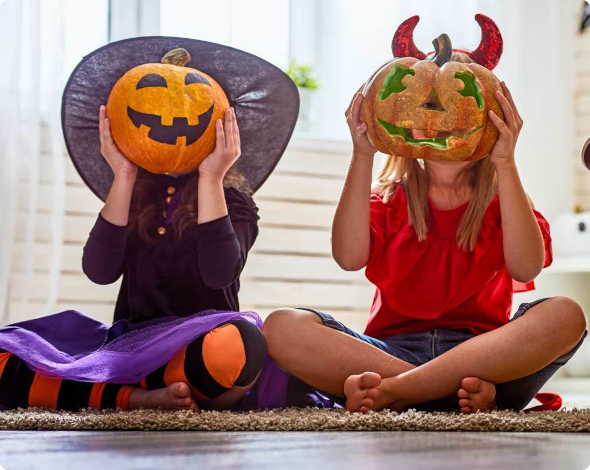 two children holding jack-o-lanterns in front of their faces